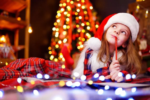 Zabawna dziewczyna w Santa hat marzy pisze list do Santa — Zdjęcie stockowe