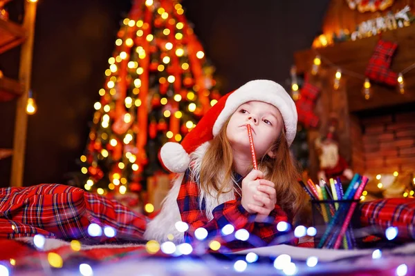 Zabawna dziewczyna w Santa hat marzy pisze list do Santa — Zdjęcie stockowe