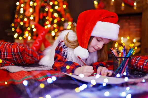 Zabawna dziewczyna w santa hat pisze list do santa — Zdjęcie stockowe