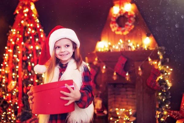 Чарівна маленька дівчинка відкриває чарівний різдвяний подарунок на ялинку в затишній вітальні взимку — стокове фото