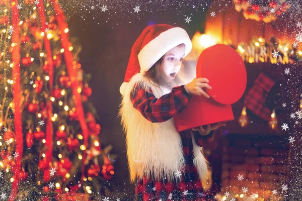 Чарівна маленька дівчинка відкриває чарівний різдвяний подарунок на ялинку в затишній вітальні взимку — стокове фото