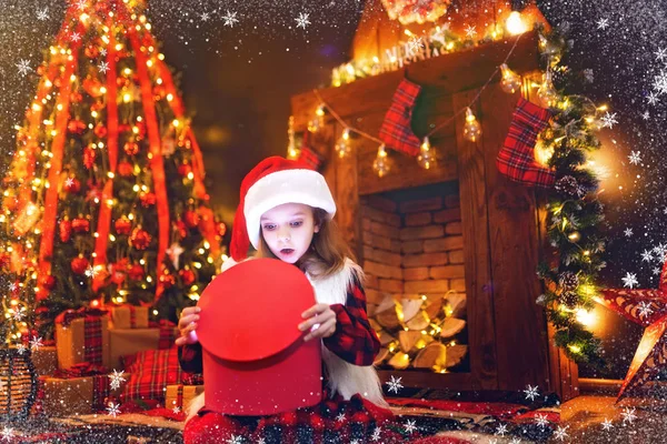 Bedårande liten flicka öppna en magisk julklapp av en julgran i mysiga vardagsrum i vinter — Stockfoto