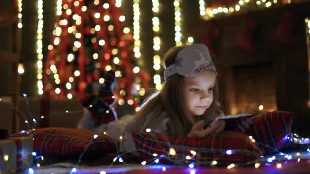 Menina brincando com tablet, smartphone perto da árvore de Natal — Vídeo de Stock