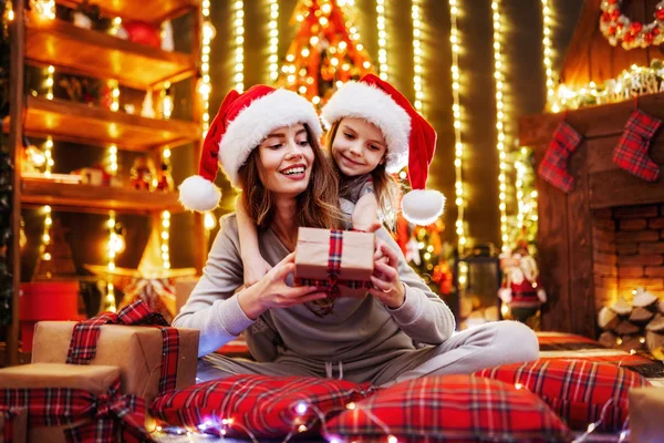 Glad mamma och hennes söta dotter flicka utbyter gåvor. Förälder och barn ha roligt nära träd inomhus. Kärleksfull familj med presenterar i jul rum. — Stockfoto