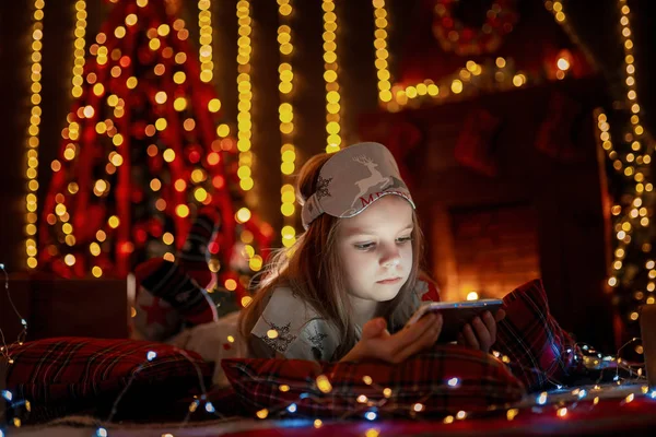 Petite fille couchée sur le tapis avec des cadeaux autour en utilisant la tablette sur — Photo