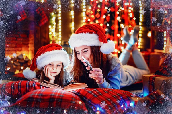 Jonge moeder met haar dochtertje lezen van een boek terwijl sitti — Stockfoto