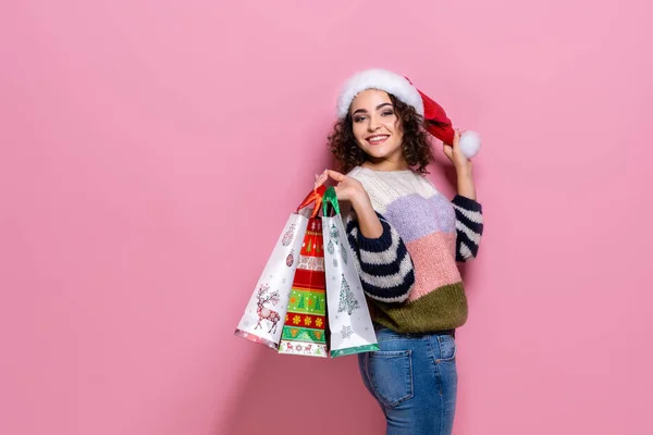 Beautiful women wearing bright Christmas carrying colorful shopping bags. On pink background. Christmas shopping And happy new year. — Stock Photo, Image