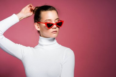 Muhteşem zarif kadın beyaz örme golf ve pembe duvardan poz güneş gözlüğü.