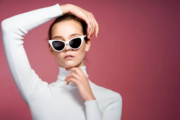 Preciosa mujer elegante en golf de punto blanco y gafas de sol posando sobre la pared rosa . —  Fotos de Stock