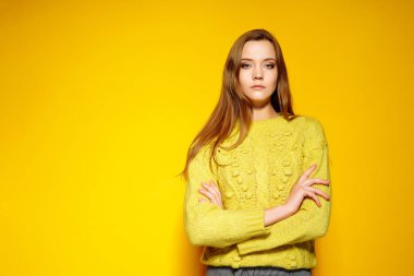 Güzel kadın model geçti ellerini tutar, rahat comfrotable kazak giyer, sarı arka planı teşkil etmektedir. Boşaltmak