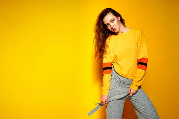 Vacker kvinnlig modell bär casual comfrotable tröja, poserar mot gul bakgrund. Copyspace — Stockfoto