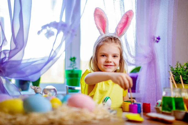 Happy easter dziewczyna w uszy królika, malowanie pisanek, małe dziecko w domu. Święto wiosny — Zdjęcie stockowe