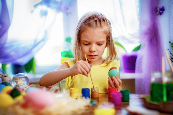 Menina feliz pintando ovos de páscoa, criança pequena em casa se divertir. férias de primavera — Fotografia de Stock