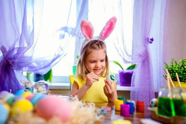 Happy easter dziewczyna w uszy królika, malowanie pisanek, małe dziecko w domu. Święto wiosny — Zdjęcie stockowe