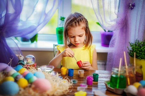 Щаслива дівчина, яка малює великодні яйця, маленька дитина вдома розважається. весняне свято — стокове фото