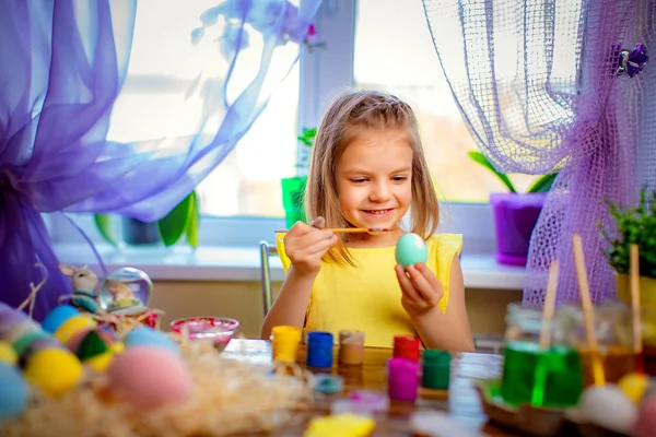 Щаслива дівчина, яка малює великодні яйця, маленька дитина вдома розважається. весняне свято — стокове фото