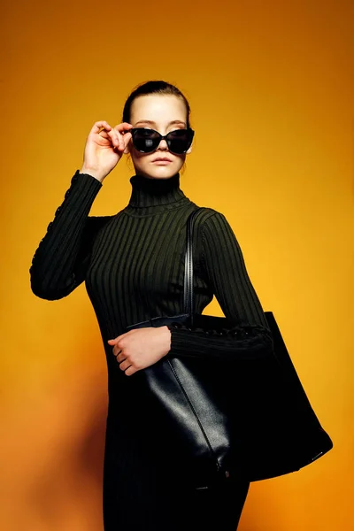 Venerdì nero concetto di vendita. Shopping donna in possesso di borsa in pelle nera isolato su sfondo giallo — Foto Stock