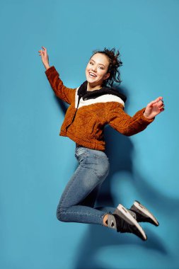 Casual havada mavi arka plan üzerinde atlama içinde genç kadın