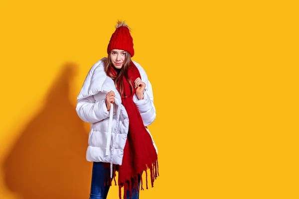 Snygg ung kvinna i en vit päls och knite röd hatt på gul bakgrund — Stockfoto