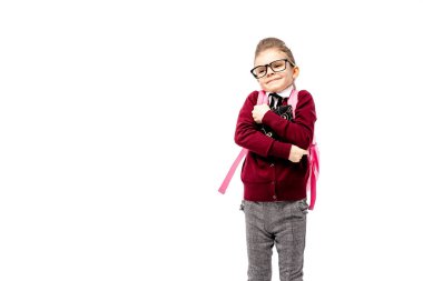 Çantanı çocukla. Kız beyaz gömlek ve gri pantolon, yuvarlak gözlük, bir kitap, okul çantası tutun ve model gibi poz puan parmak. Beyaz izole