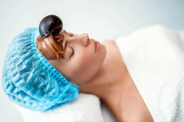 Mladá žena podstupující léčbu s obří šneky Oblovka v salonu krásy — Stock fotografie