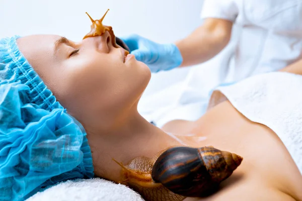 Young woman undergoing treatment with giant Achatina snails in beauty salon — Stock Photo, Image