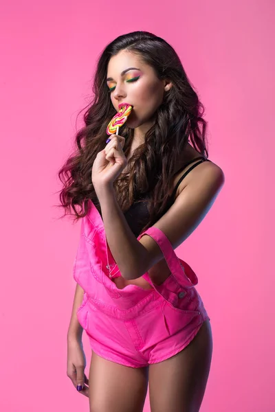 롤리팝과 분홍색 배경에서 카메라 포즈 죄수 복에 재미 있는 어린 소녀 — 스톡 사진
