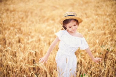 Mutlu çocuk sonbahar buğday alanında. Güzel kız beyaz elbise ve hasır şapka iyi eğlenceler oynarken, hasat