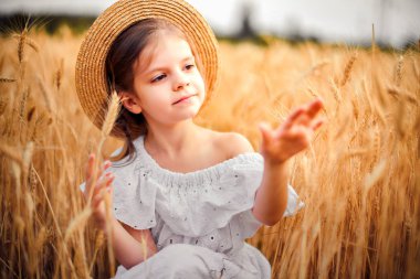 Mutlu çocuk sonbahar buğday alanında. Güzel kız beyaz elbise ve hasır şapka iyi eğlenceler oynarken, hasat