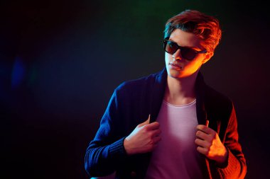 Siyah ceket ve güneş gözlüğü serin şık adam. Yüksek moda erkek modeli siyah arka plan üzerine poz renkli parlak neon ışıkları. Sanat tasarım konsepti