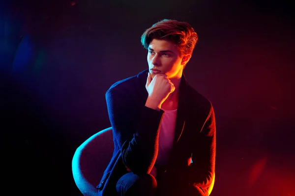 High Fashion male model in colorful bright neon lights posing on black background. Art design concept