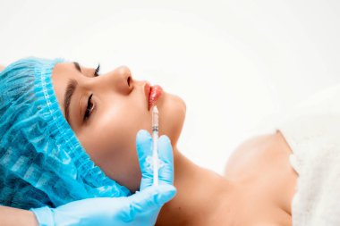 Doktor kozmetik uzmanı güzellik salonundaki bir kadının cildindeki kırışıklıkları sıkılaştırmak ve düzleştirmek için yüz enjeksiyonlarını yenileyen prosedürü uyguluyor. Kozmetoloji cilt bakımı