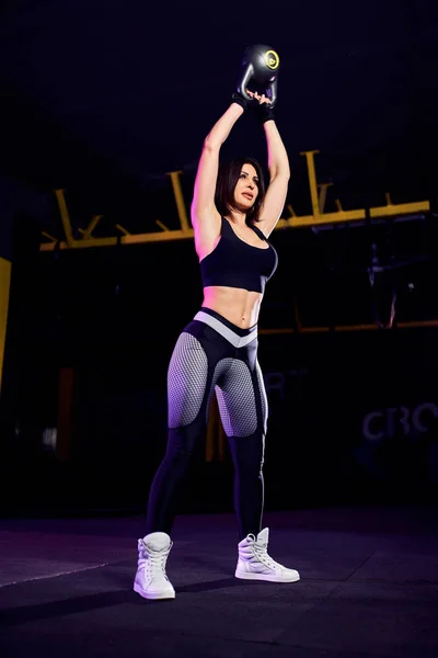 Attractive fit middle age womanathlete performing a kettle-bell swing — Stock Photo, Image