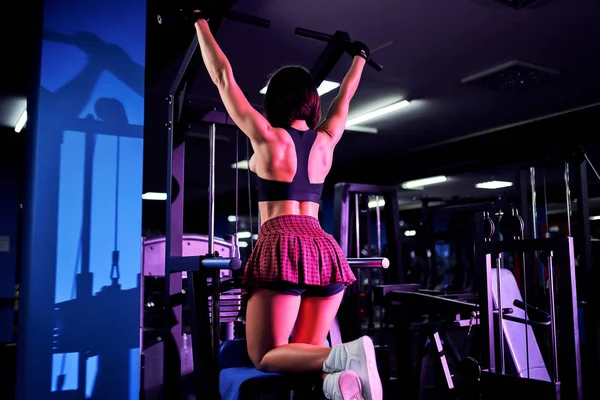 Sportovní žena dělá cvičení pro záda, pomocí počítače, v tělocvičně - zadní pohled — Stock fotografie
