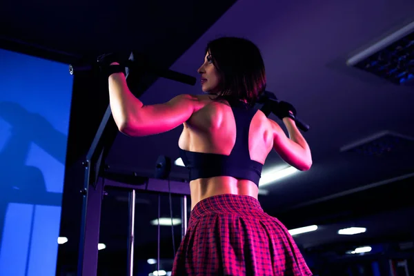 Mujer atlética haciendo ejercicio para la espalda, utilizando la máquina, en el gimnasio - vista trasera — Foto de Stock