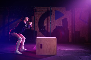 Çekici uygun orta yaş kadın bir Cross fit tarzı atlama kutusu yapıyor. Kadın atlet spor salonunda atlar performans