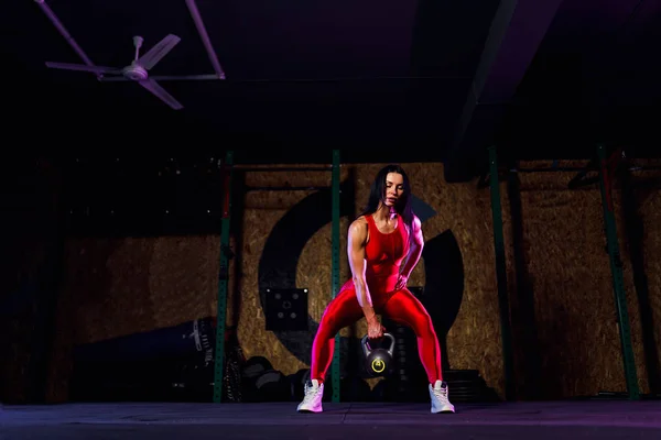 Aantrekkelijke fitte vrouw atleet het uitvoeren van een ketel-bel swing in de sportschool — Stockfoto