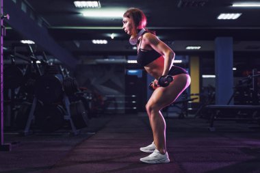 Spor salonundaki çekici fit seksi kadın halterle çömeliyor. Kadın antrenmanı