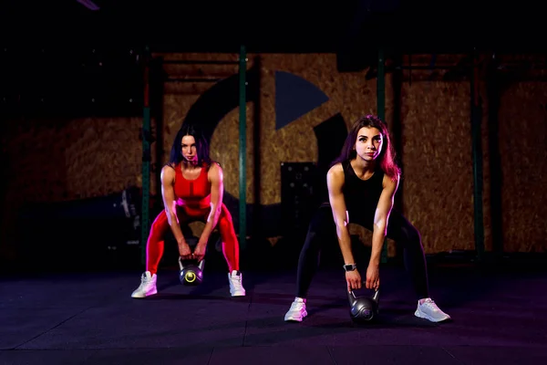 Dos mujeres atletas atractivas en forma realizando un swing de timbre en el gimnasio —  Fotos de Stock