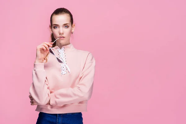 Young pretty woman in pink sweater and sunglasses isolated on pink studio background — 스톡 사진