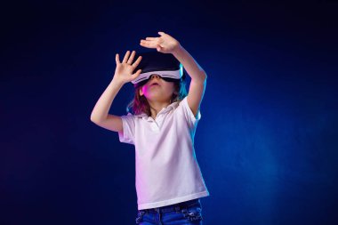 Kız 7 y.o. renkli arka planda Vr kulaklık oyunu yaşıyor. Çocuk sanal gerçeklik için bir oyun gadget kullanarak.