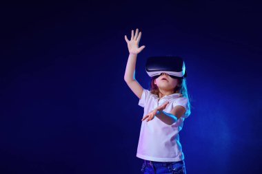 Kız 7 y.o. renkli arka planda Vr kulaklık oyunu yaşıyor. Çocuk sanal gerçeklik için bir oyun gadget kullanarak.