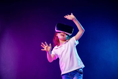 Kız 7 y.o. renkli arka planda Vr kulaklık oyunu yaşıyor. Çocuk sanal gerçeklik için bir oyun gadget kullanarak.