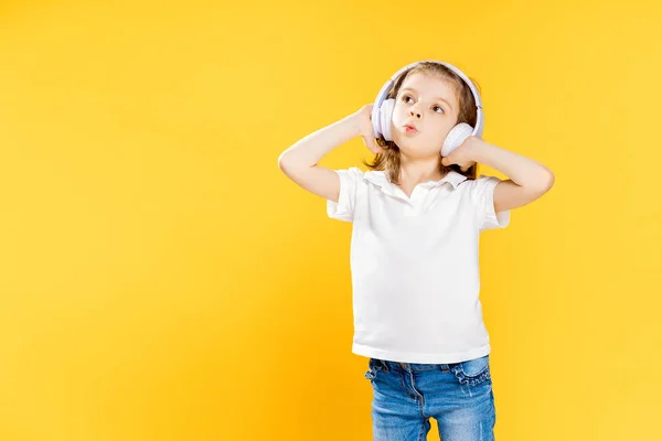 Chica escuchando música en auriculares inalámbricos sobre fondo amarillo. Bailarina. Feliz niña bailando música. Lindo niño disfrutando de música de baile feliz . — Foto de Stock