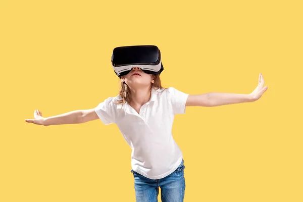 Menina 7 y.o em roupa formal vestindo óculos VR colocando as mãos para fora em excitação isolada no fundo amarelo. Criança usando um gadget de jogo para realidade virtual. Tecnologia virtual — Fotografia de Stock