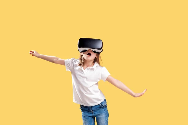 Menina 7 y.o em roupa formal vestindo óculos VR colocando as mãos para fora em excitação isolada no fundo amarelo. Criança usando um gadget de jogo para realidade virtual. Tecnologia virtual — Fotografia de Stock