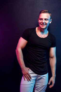 Parti sırasında renkli aydınlatma altında poz trendy kıyafeti kendine güvenen adam