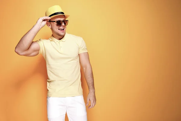 Tipo con estilo de confianza en camisa amarilla, gafas de sol, pantalones cortos blancos, sombrero de paja mirando al lado de la cámara — Foto de Stock