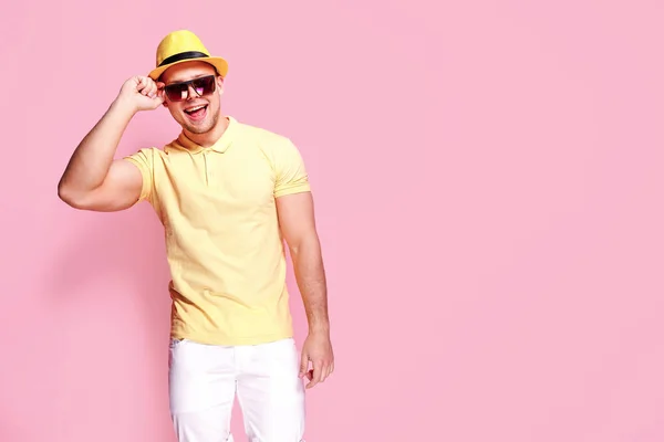 Zelfverzekerd stijlvolle kerel in geel shirt, zonnebril, witte shorts, stro hoed kijken naar camera — Stockfoto