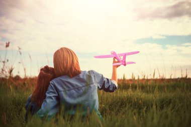 Unrecognizable mother and daughter playing with plane in meadow